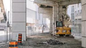 Ein gelber Bagger bei Bauarbeiten an einer großen Beton-Autobahnbrücke.
