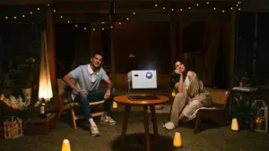 Ein Paar genießt einen gemütlichen Filmabend mit einem Projektor in einem beleuchteten Garten.