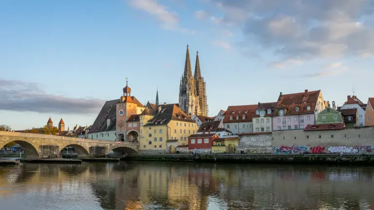 Der Regensburger Dom mit der historischen Altstadt und der Donau im Sonnenlicht.
