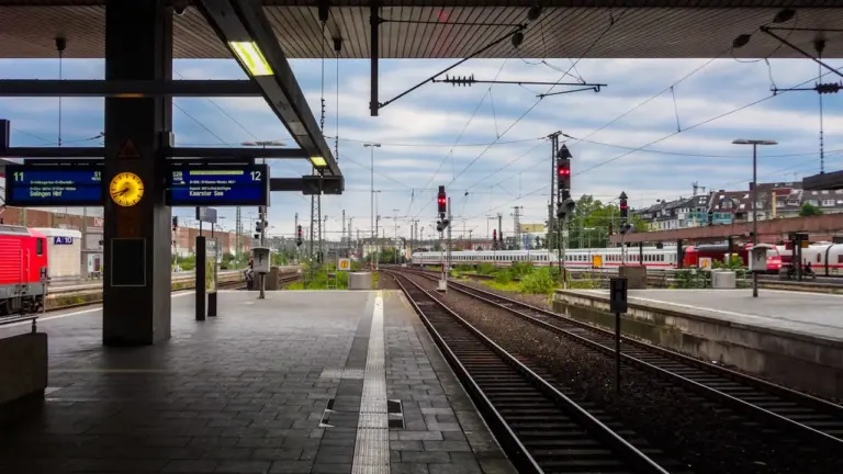 Moderner Bahnsteig in Deutschland mit Gleisen und digitalen Fahrgastinformationen an einem bewölkten Tag.