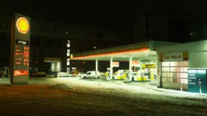 Nächtliche Shell-Tankstelle mit Preistafel bei winterlichem Wetter und Schnee.