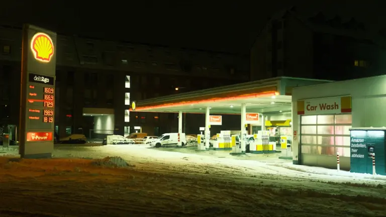 Nächtliche Shell-Tankstelle mit Preistafel bei winterlichem Wetter und Schnee.