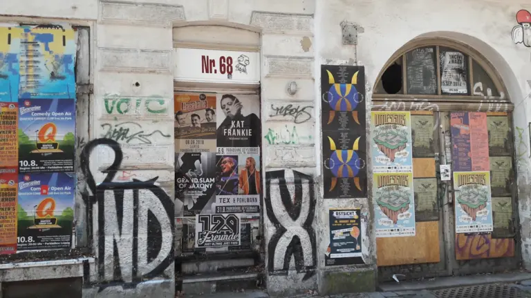 Eine von Streetart und Graffiti geprägte Hauswand mit hohen Türen in Leipzig.