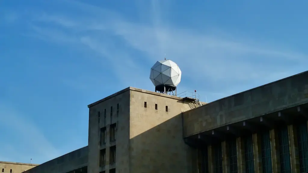 Ein weißer Wetterradardom auf einem historischen Gebäude unter einem strahlend blauen Sommerhimmel.