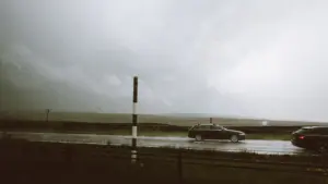 Autos fahren bei starkem Regen und schlechter Sicht über eine überflutete Landstraße.