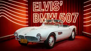 Der legendäre weiße BMW 507 von Elvis Presley auf einer roten Ausstellungsplattform.