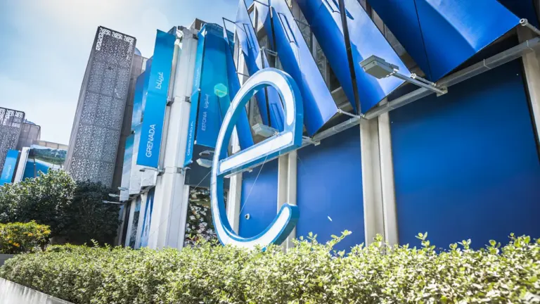 Modernes Bürogebäude mit blauem Logo vor klarem Himmel für Wirtschaftsberichterstattung.