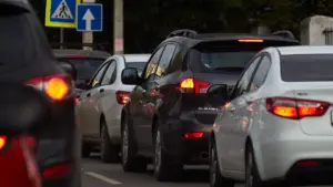 Dichte Autokolonne auf einer Straße mit Verkehrsschildern bei Tageslicht.