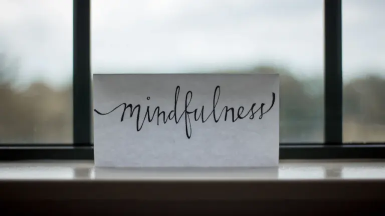 Ein Blatt Papier mit der Aufschrift Mindfulness liegt vor einem hellen Fenster.