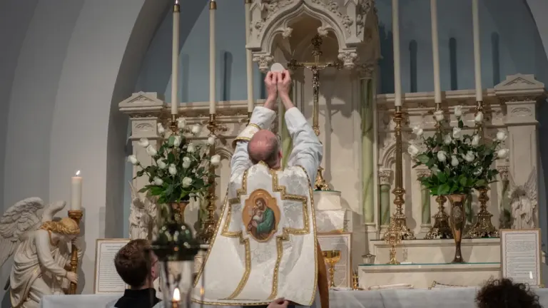 Katholischer Priester bei der Feier der heiligen Messe am Altar in einer Kirche.