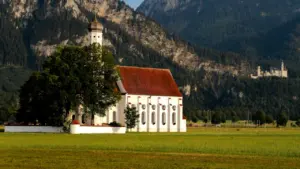Eine malerische Kirche vor einer beeindruckenden Bergkulisse in der bayerischen Landschaft.