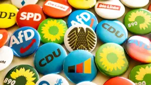 Verschiedene politische Buttons der deutschen Parteien liegen auf einem Tisch verteilt.