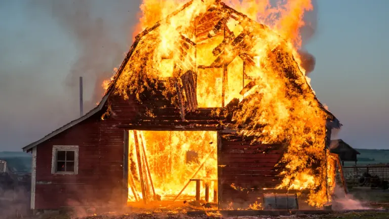Eine brennende hölzerne Scheune steht bei Nacht in hellen Flammen.