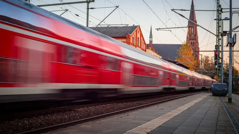 Ein einfahrender Regionalzug in einem Bahnhof in Deutschland bei bewölktem Wetter.