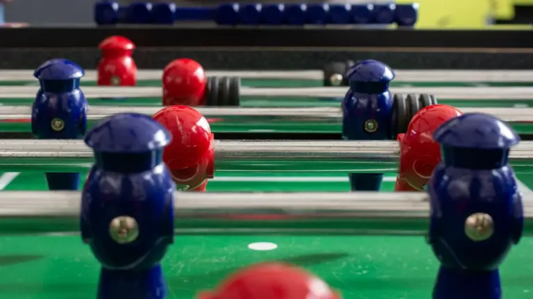 Bunter Tischkicker mit blauen und roten Spielfiguren im Detailansicht.