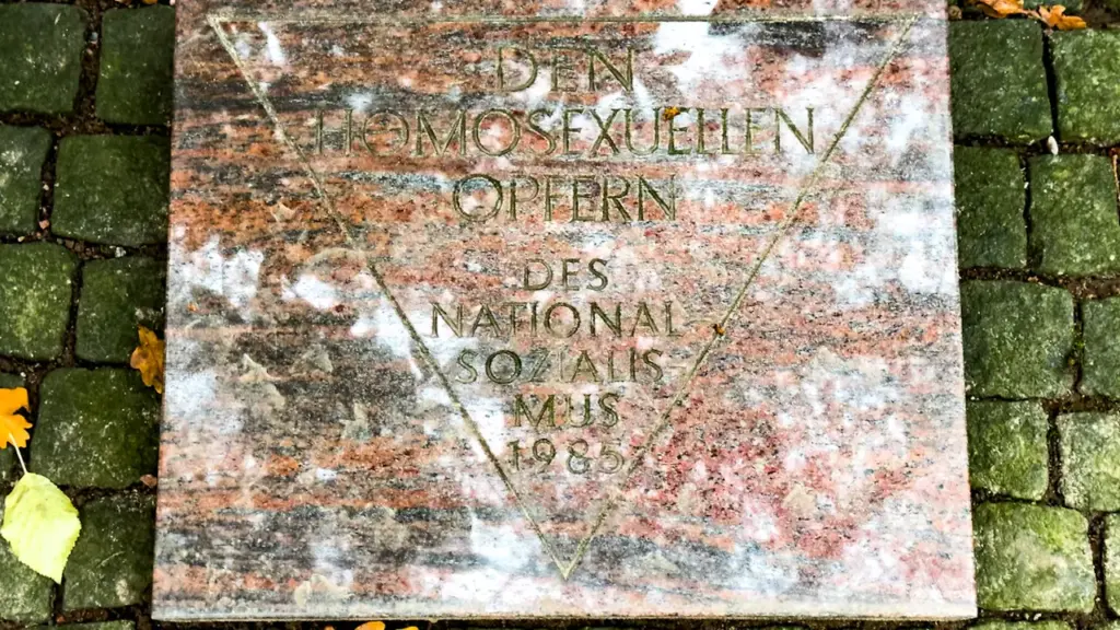 Gedenkstein für homosexuelle NS-Opfer mit eingraviertem rosa Winkel auf Steinboden