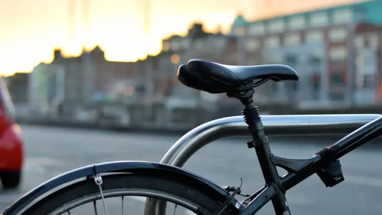 Ein am Fahrradständer angeschlossenes Fahrrad in einer urbanen Umgebung bei Sonnenuntergang.