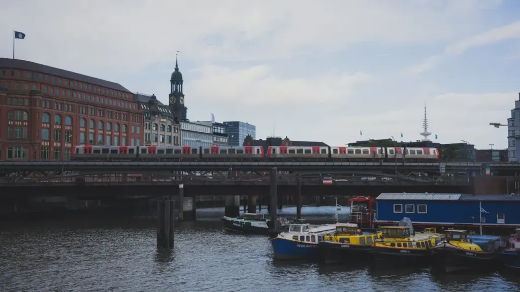 Eine S-Bahn überquert eine Hamburger Brücke über die Elbe bei bewölktem Himmel.