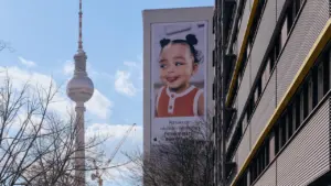 Der Berliner Fernsehturm neben einer Plakatwand mit dem Bild eines jungen Kindes.