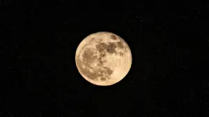 Ein heller Vollmond leuchtet scharf vor einem tiefschwarzen, sternenübersäten Nachthimmel im Weltraum.