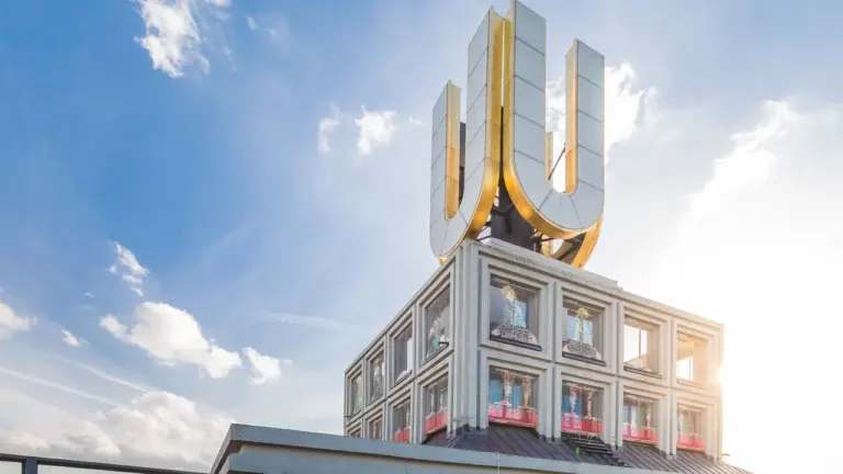 Das Dortmunder U mit dem goldenen, leuchtenden U-Logo auf dem Dach bei blauem Himmel.