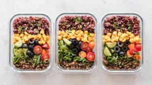 Drei Glasbehälter mit gesunden Mahlzeiten, bestehend aus Reis, Gemüse und Linsen für Meal Prep.