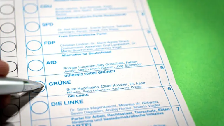 Ein Stimmzettel für eine deutsche Wahl mit einem Stift in der Hand.