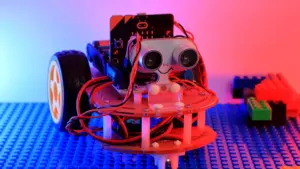 Ein kleiner, selbstgebauter Roboter mit Sensoren steht auf einer blauen Lego-Platte.