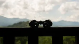 Schwarzes Fernglas auf einem Metallgeländer bereit für die abendliche Beobachtung des Sternenhimmels.