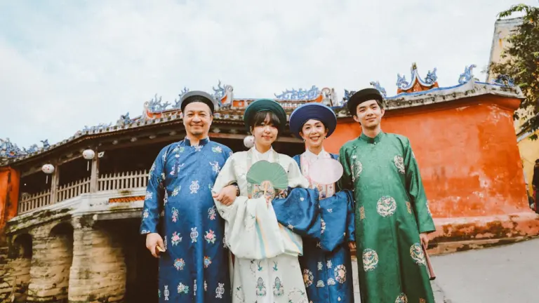 Familie in traditioneller Kleidung vor einer historischen Brücke an einem sonnigen Tag.