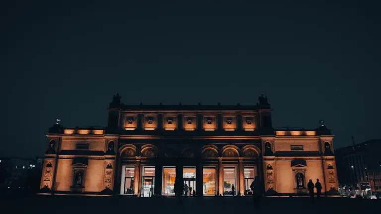 Die Hamburger Kunsthalle bei Dämmerung mit beleuchteter Fassade und Besuchern.