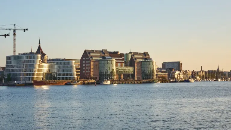 Die Warnow und die Skyline von Rostock bei spätem Nachmittagslicht am Hafen.