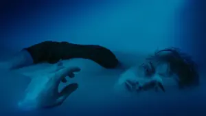 Ein Mann liegt im dunklen Wasser und symbolisiert das Eintauchen in die Gefühlswelt der Träume.